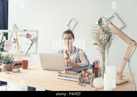 attractive businesswoman working with laptop while sitting at table in modern office Stock Photo