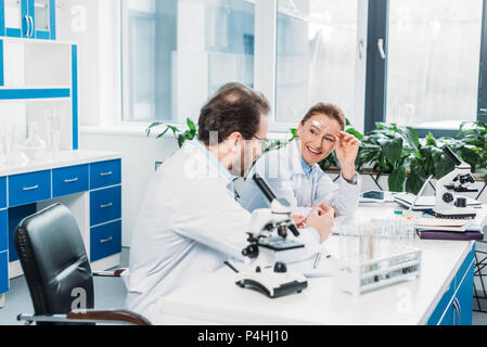 scientists in lab coats and eyeglasses discussing work at workplace in lab Stock Photo