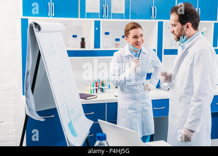 scientist in white coats near board for notes having discussion during work in lab Stock Photo