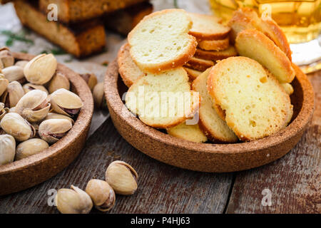 Snacks to beer, crackers, salted pistachios and a glass of light beer in the background on a wooden table. Stock Photo