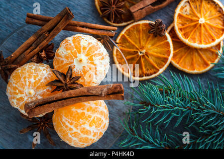 Mandarins, dried oranges, anise and cinnamon sticks on a wooden table next to the fir branch Stock Photo