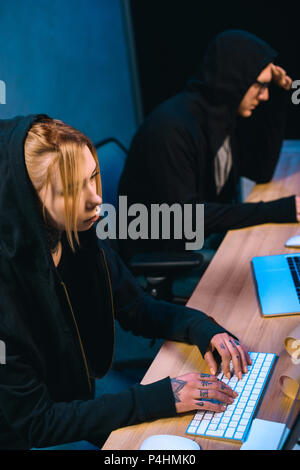 high angle view of serious female hacker working on new malware with accomplice  in dark room Stock Photo