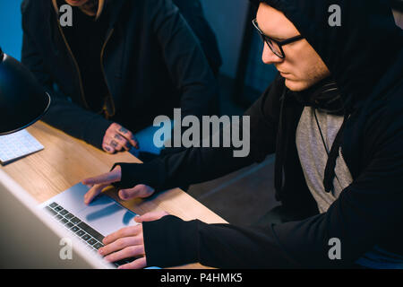 serious hacker working on new malware with accomplice  in dark room Stock Photo