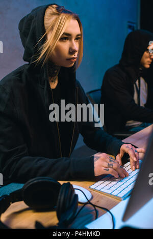 female hacker working on new malware with accomplice  in dark room Stock Photo