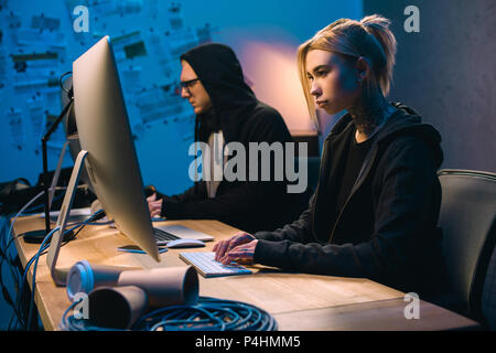 confident couple of hackers working on malware in dark room Stock Photo
