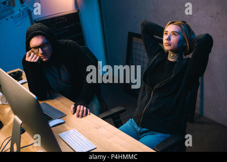 couple of thoughtful young hackers at workplace Stock Photo