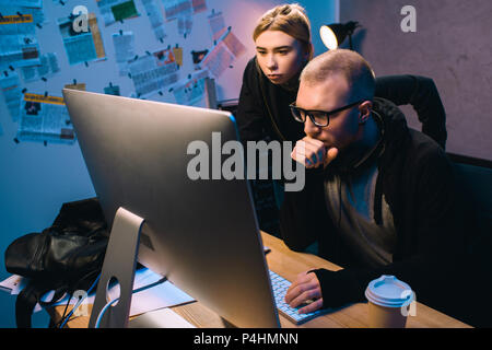 serious couple of hackers working with computer together in dark room Stock Photo