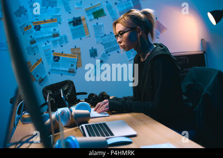 side view of young female hacker developing malware in dark room Stock Photo
