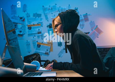 side view of female hacker developing malware in dark room Stock Photo