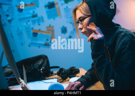 side view of serious young female hacker holding bitcoin Stock Photo