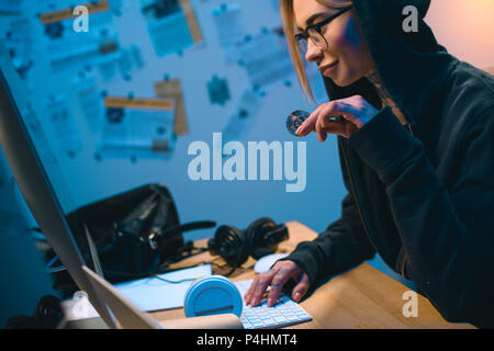 side view of young female hacker holding bitcoin Stock Photo