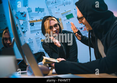 happy couple of hackers with stack of cash giving high five Stock Photo