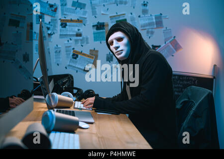 hacker in mask developing malware at his workplace Stock Photo