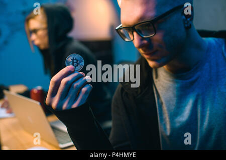 close-up shot of young handsome hackers holding bitcoin Stock Photo