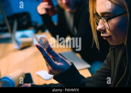 close-up shot of female hackers holding bitcoin Stock Photo