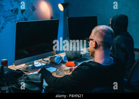hackers working on malware together in dark room Stock Photo