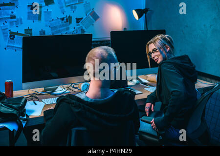 young couple of hackers working on malware together in dark room Stock Photo