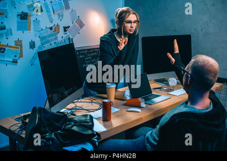 couple of hackers giving high five at desk in dark room Stock Photo