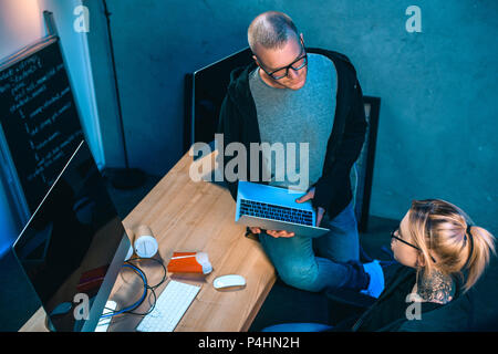 high angle view of couple of hackers working on malware together in dark room Stock Photo