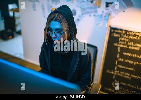 high angle view of female hacker developing malware under blue light Stock Photo