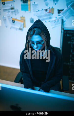 high angle view of young female hacker developing malware under blue light Stock Photo