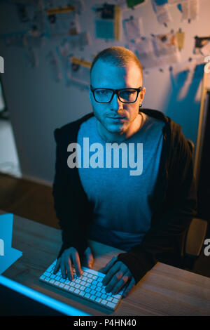 high angle view of hacker sitting at workplace and looking at camera Stock Photo