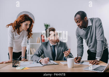 Three businesspeople doing paperwork at table in office Stock Photo