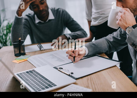 Financial adviser drinking coffee and writing while clients waiting Stock Photo