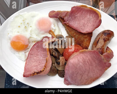 English cooked breakfast, fry up,fried eggs,sausage,fried bacon,mushrooms,tomato,fried bread,on a plate Stock Photo