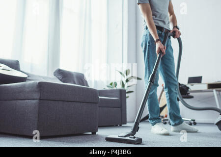 cropped view of young man cleaning floor with vacuum cleaner Stock Photo