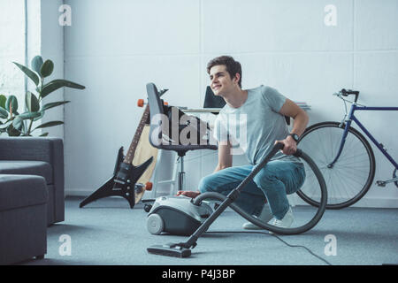 smiling teenager cleaning floor with vacuum cleaner in living room Stock Photo