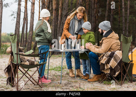 family drinking hot tea outdoors on autumn hiking trip Stock Photo