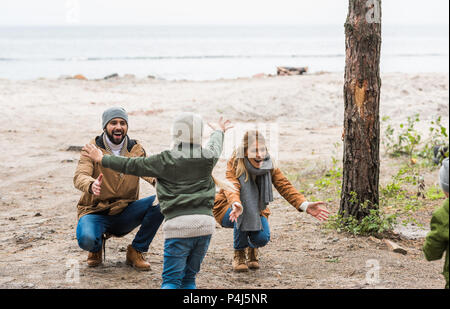 kids running to happy parents on seashore on cold autumn day Stock Photo