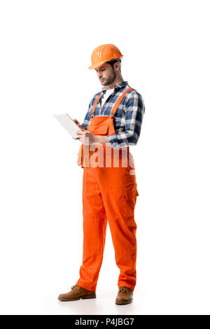 Young repairman in orange overall and hard hat using digital tablet isolated on white Stock Photo