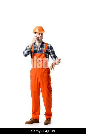 Young repairman in orange overall and hard hat talking on the phone isolated on white Stock Photo