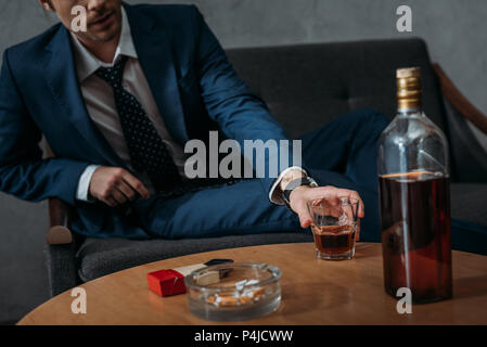 cropped shot of businessman taking glass of whiskey from table Stock Photo