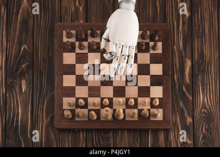 cropped shot of robot playing chess on wooden surface Stock Photo