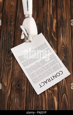 cropped shot of robot signing business contract on wooden surface Stock Photo