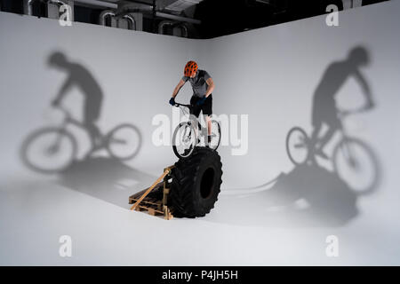 young trial biker in helmet balancing on tractor wheel Stock Photo
