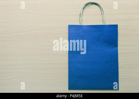 Blue Paper bag is placed on a brown wooden floor and have copy space for design in your work. Stock Photo