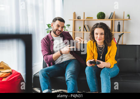 Man pointing fingers at his girlfriend while she holding joystick Stock Photo