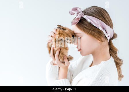 side view of beautiful little girl holding furry rabbit isolated on white Stock Photo