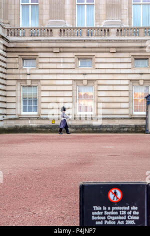 Queen's foot guard marching along the Buckingham Palace in the winter grey great-coat and a bearskin cap. Stock Photo