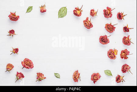 Dried roses flowers on vintage rustic white wooden desk as background.Top  view. Concept of love and  romantic  and passing of time Stock Photo