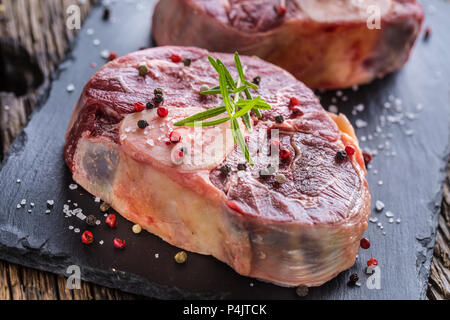 Two pieces raw beef shank on slate board and wooden table.. Stock Photo