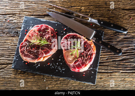 Two pieces raw beef shank on slate board and wooden table.. Stock Photo