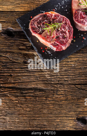 Two pieces raw beef shank on slate board and wooden table.. Stock Photo
