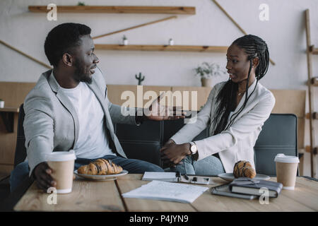 side view of african american business partners having conversation at table in coffee shop