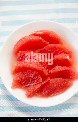 Red grapefruit pieces, segments on white plate Stock Photo