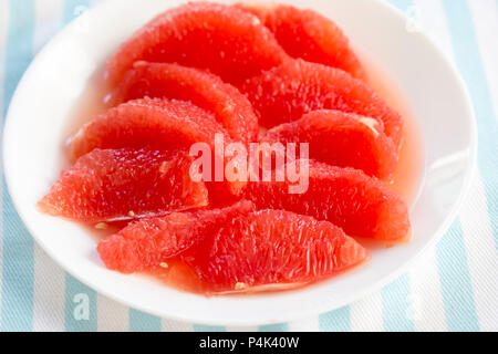 Red grapefruit pieces, segments on white plate Stock Photo